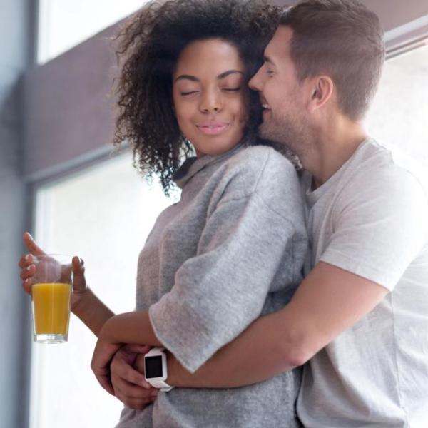 Couple in a relaxed embrace by a window, symbolising safety, connection, and nervous system regulation in intimacy